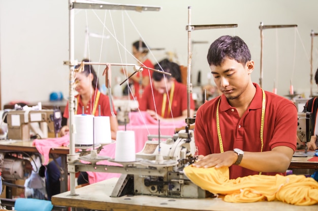 Man sewing on a sewinghine at a clothing factory